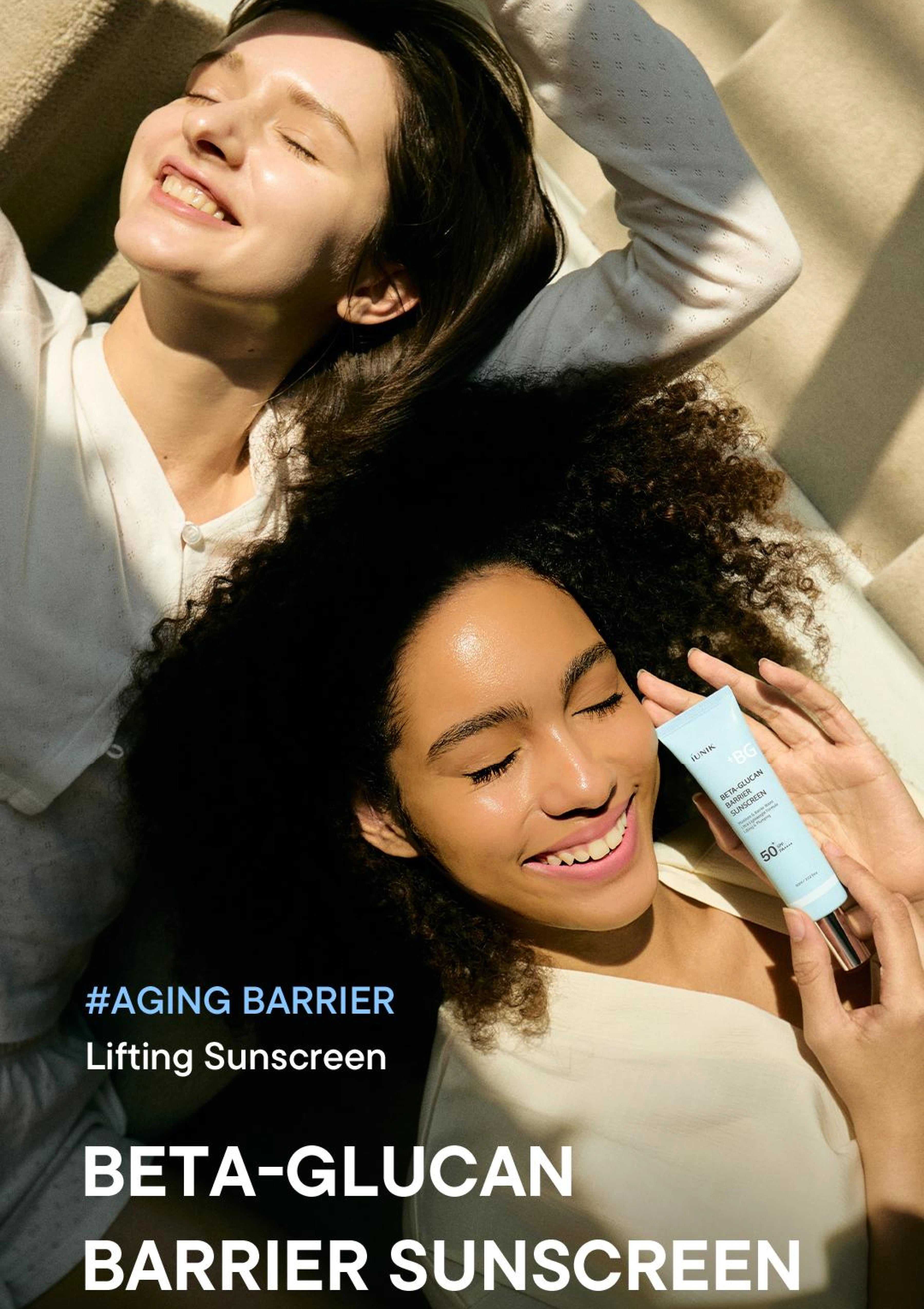 Two women lying on a beach with sunscreen product, featuring text about aging barrier and beta-glucan barrier sunscreen.